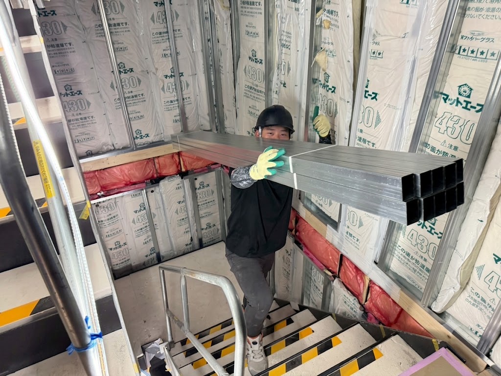 有田屋の職人が建設現場で軽量鉄骨材を搬入する様子