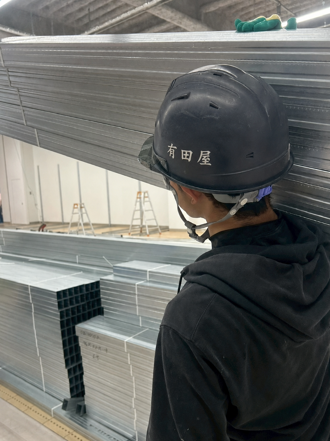 有田屋のロゴ入りヘルメットを着用したスタッフと搬入現場の鉄骨材